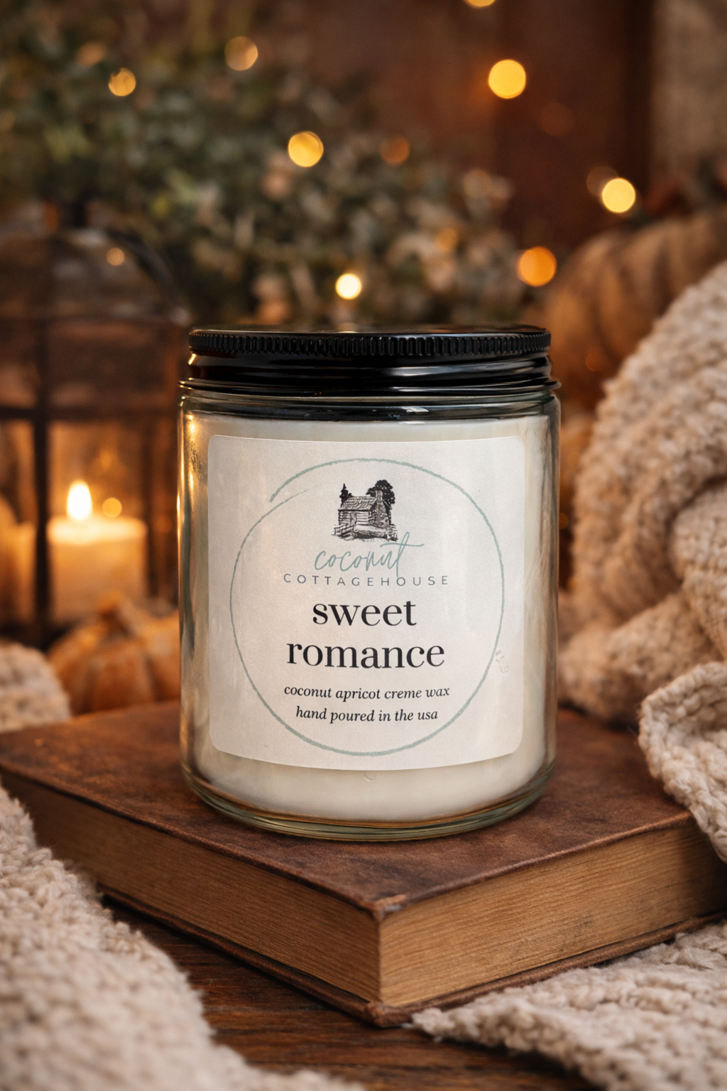A glass jar candle labeled "Sweet Romance" sits on a wooden surface, with a blurred background featuring a cozy, warm atmosphere.
