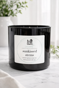 A black candle in a glass container with a label that reads "Sunkissed Stems" and "Hand Poured in the USA".